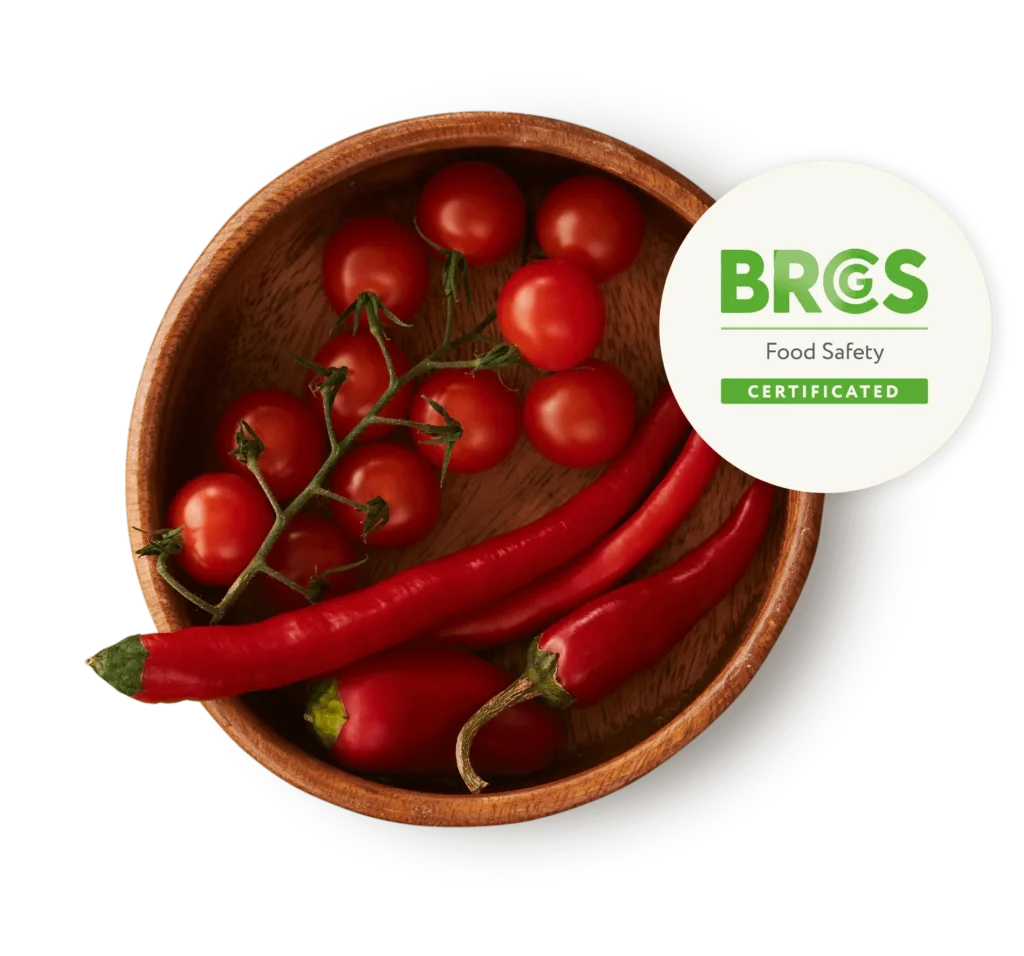 BRCGS Food Safety certification badge with fresh tomatoes and chillies representing Springbrook Foods high quality and safety standards.