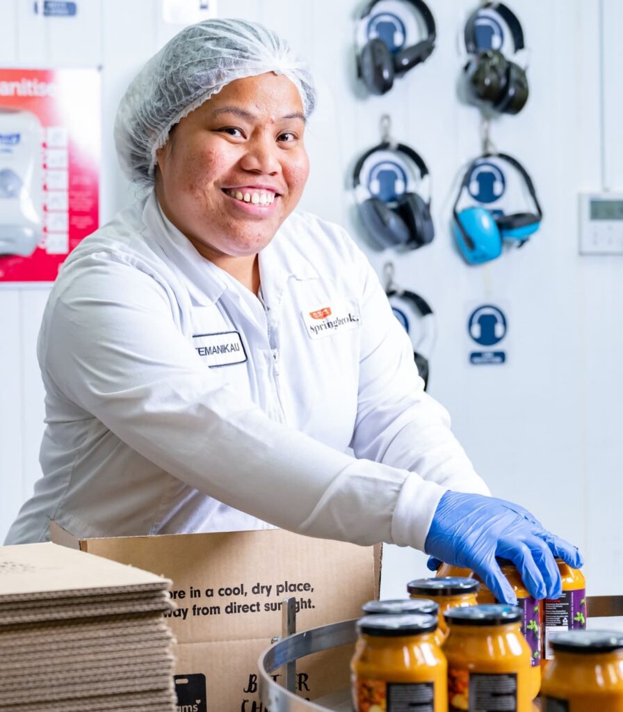 Springbrook Foods team member packing finished sauce jars in food manufacturing facility.