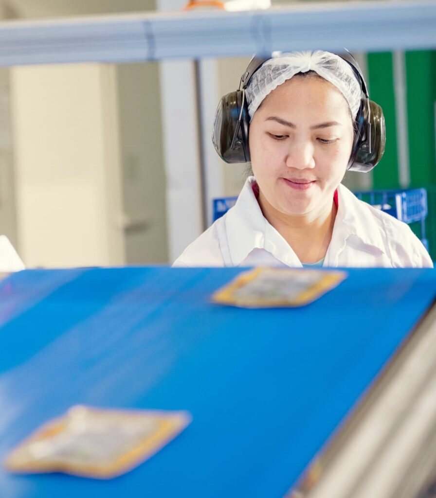 Production team member monitoring packaged products on food manufacturing line.