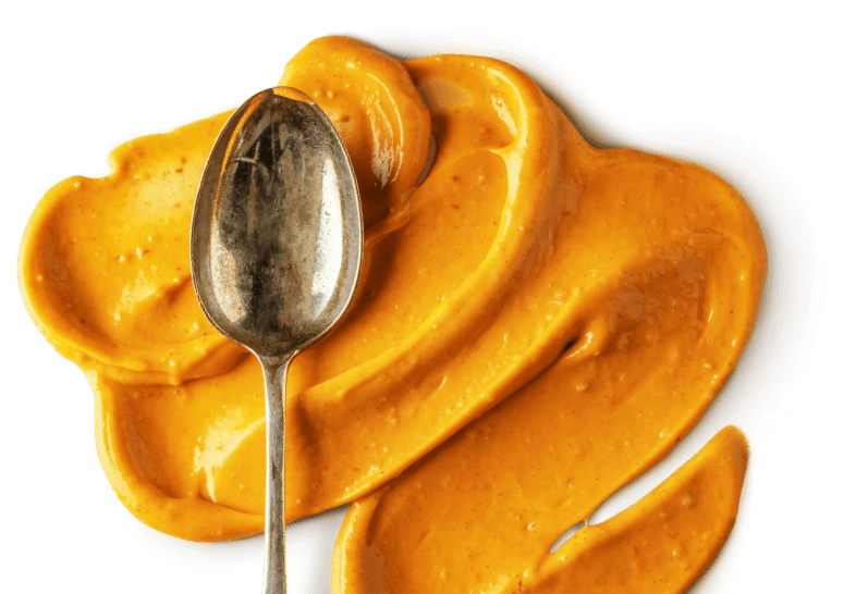Rich orange sauce texture with spoon illustrating bespoke sauce manufacturing capability.