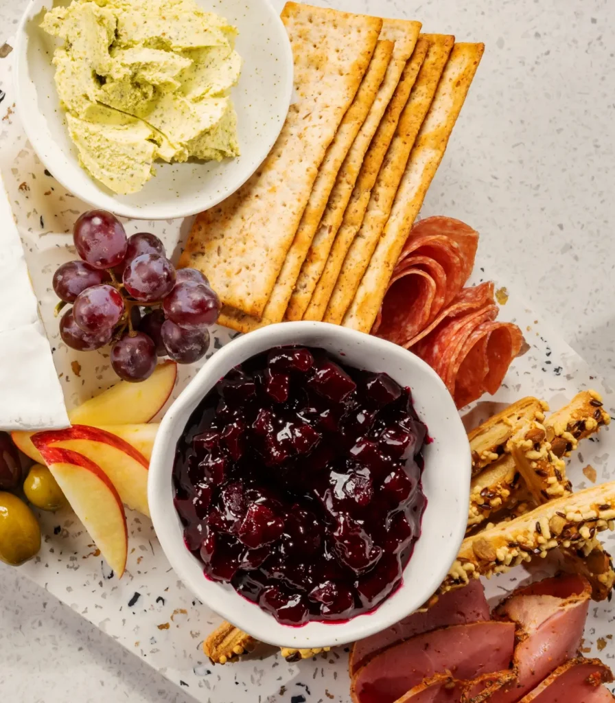 Cheese board with crackers, cured meats, Springbrook garlic and herb butter, and beetroot chutney