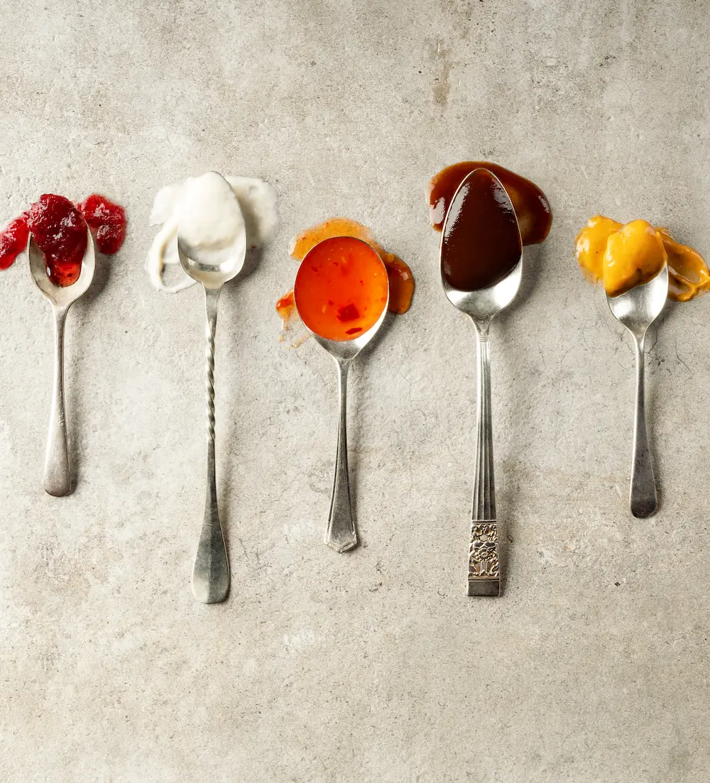 Spoons displaying a variety of sauces and textures including chutney, sweet chilli and barbecue sauce