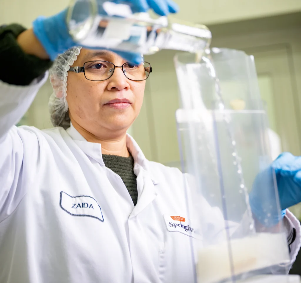 Springbrook food technologist pouring ingredients during sauce development process